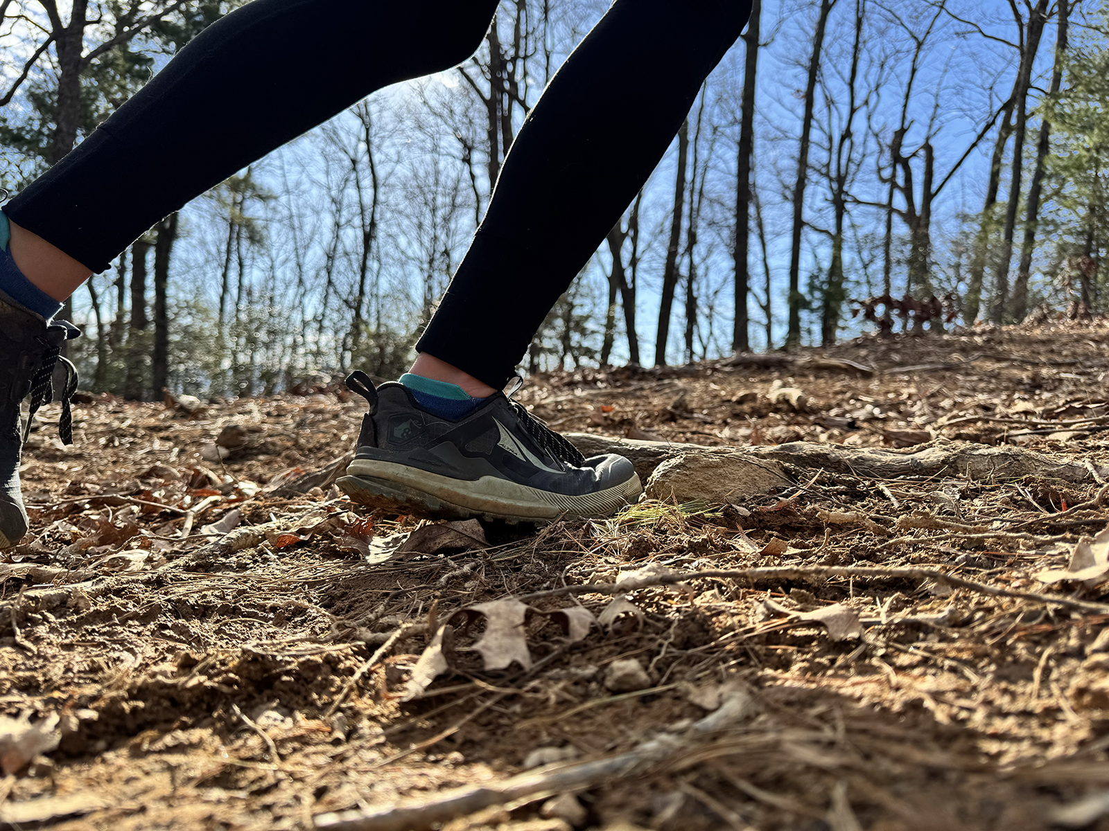 A close up of someone running by on technical terrain. The are only visible from the calf-down.